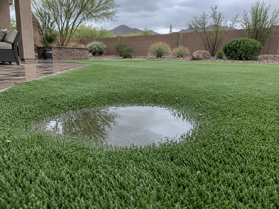 Shallow standing water collected in a low area of artificial turf after rain