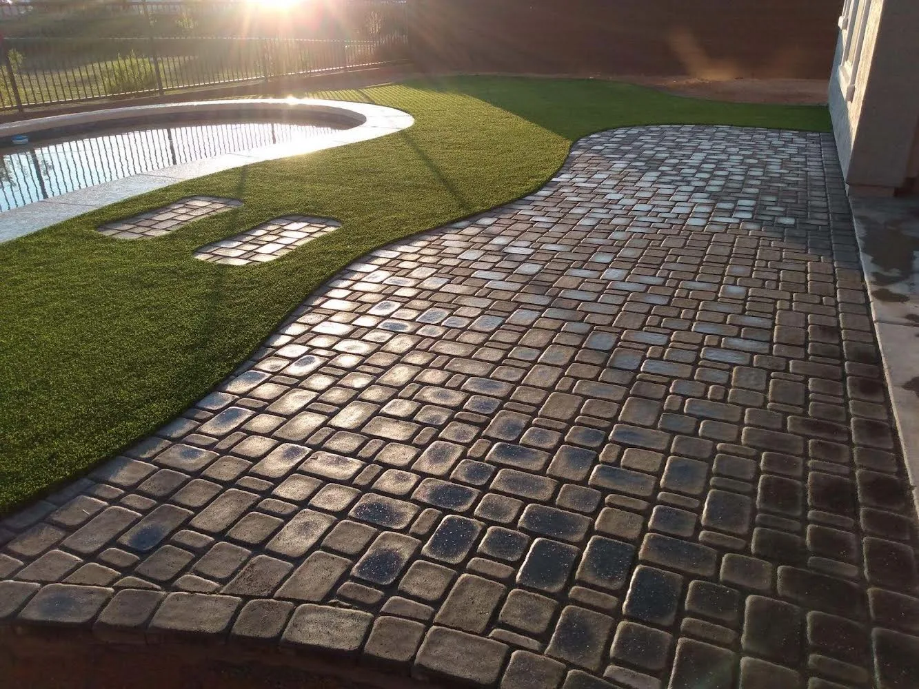 Pavers and turf near pool at sunset
